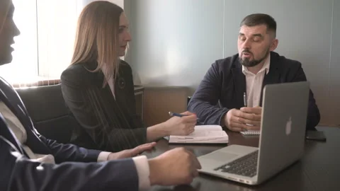 Business meeting two men and woman round the black table by a large window Stock Footage