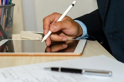 Business men are using a tablet with business documents and pens at desk. W.. Stock Photos