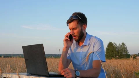 Business men at remote work. A young man works for a laptop in a wheat field. Stock Footage 136821808