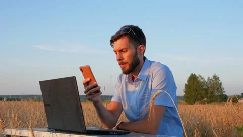 Business men at remote work. A young man works for a laptop in a wheat field. Stock Footage 136821839
