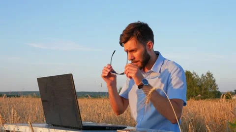 Business men at remote work. A young man works for a laptop in a wheat field. Stock Footage 136821885