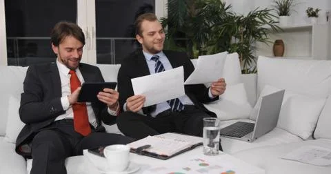 Business Men on Sofa Using Digital Tablet Discuss Good Result of Pie Chart Data Foto stock