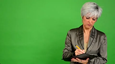 Business middle aged woman writes to paper (serious face) - green screen Stock Footage