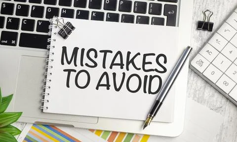 Business notebook on the keyboard with mistakes to avoid word, closeup shot Stock Photos