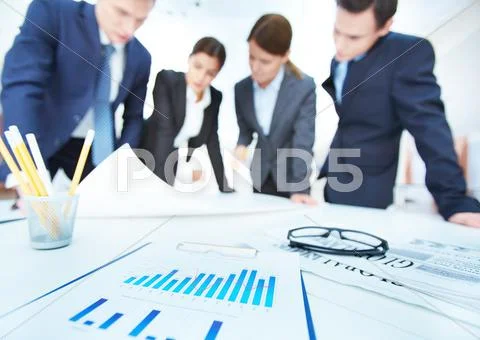 Business objects on background of engineers discussing blueprint at meeting Stock-Fotos