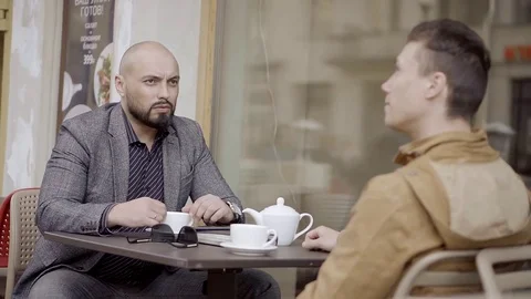Business partner discuss a strategy over a Cup of tea sitting at the table of an Stock Footage