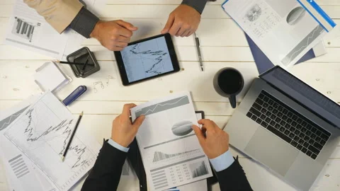 Business partners checking graphs and discussing financial reports in office Vídeos de archivo 135025684