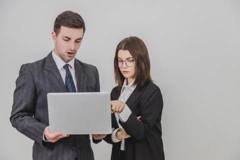 Business partners standing, checking data in the laptop. Woman is pointing her Stock Photos