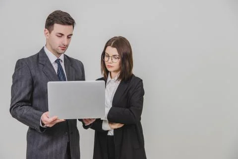 Business partners standing, checking data in the laptop. Woman is standing, her Stock Photos