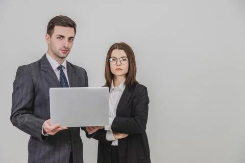 Business partners standing, checking data in the laptop. Woman is standing, her Stock Photos