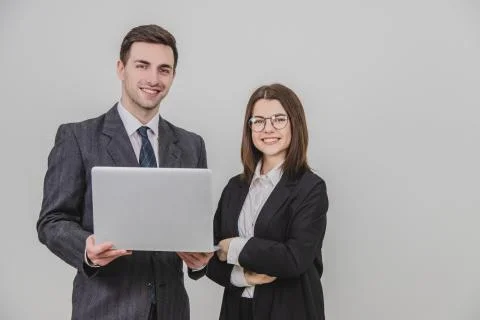 Business partners standing, checking data in the laptop, smiling happily. Woman Stock Photos