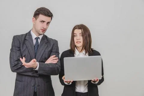Business partners standing, checking data in the laptop, looking at the camera Stock Photos