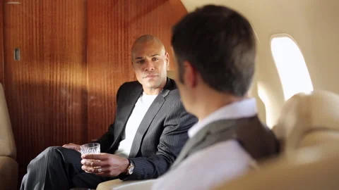 Business partners talking and drinking cocktails on private jet Stock Footage 191343726