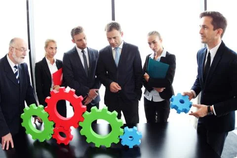 Business people assembling cogwheels Stock Photos