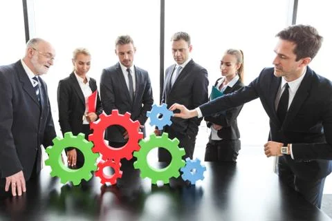 Business people assembling cogwheels Stock Photos