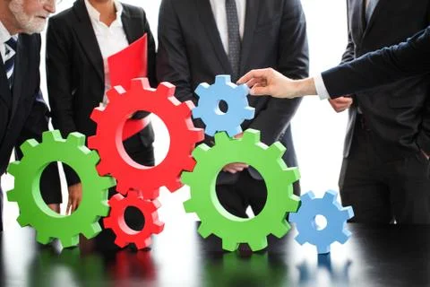 Business people assembling cogwheels Stock Photos