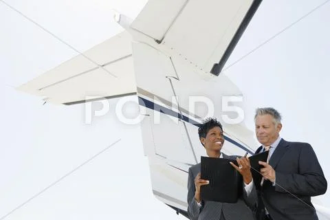Business People Discussing Below Wing Of Private Jet Stock Photos