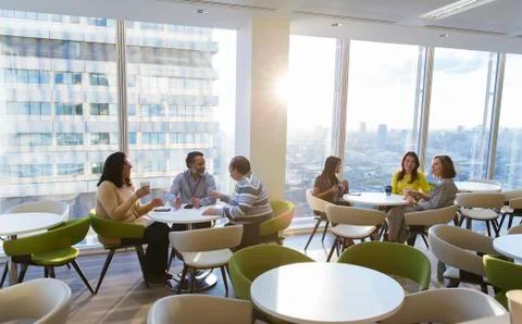 Business people eating lunch and talking in sunny highrise cafeteria Stock Photos