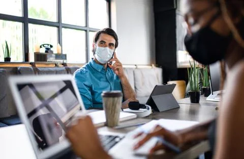Business people with face masks indoors in office, back to work after Stock Photos