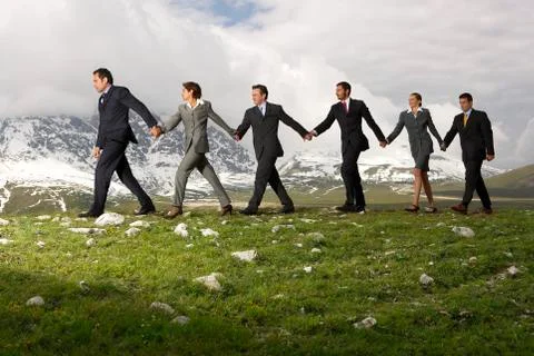 Business People Holding Hands And Walking Through Mountains Stock Photos
