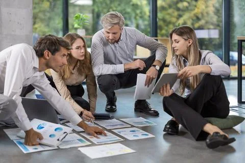 Business people looking at project plan laid out on floor, discussing new Stock Photos