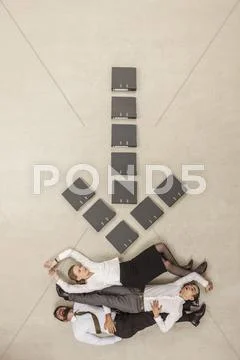 Business people lying below down arrow sign formed by files ~ Hi Res ...