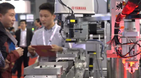 Business people networking behind automatic assembly line at trade show China Video stock 60434720