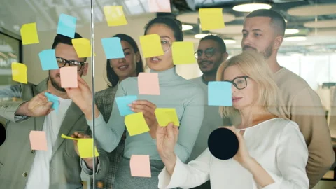 Business people solving business problems in office using sticky notes on glass Stock Footage 130862279