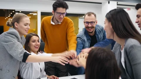 Business people stack hands in pile over meeting table, cheer together in Stock Footage 195093302