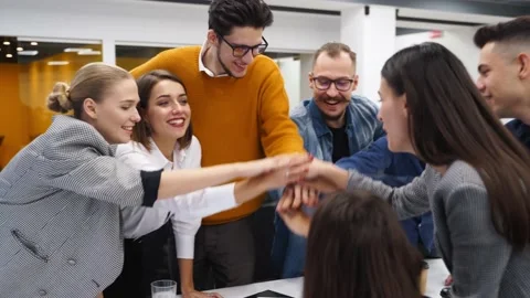 Business people stack hands in pile over meeting table, cheer together in Stock Footage 197942595