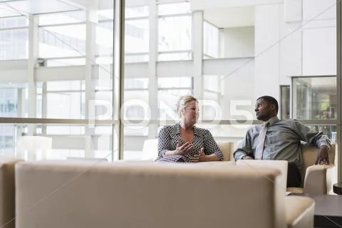 Business People Talking In Lobby Armchairs
