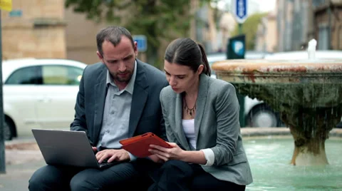 Business people talking, using laptop and tablet, sitting on fountain HD Stock Footage 32173051