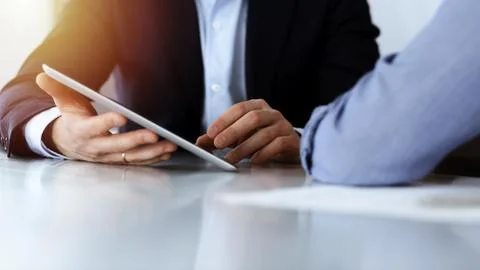 Business people using tablet computer while working together in sunny modern Foto stock