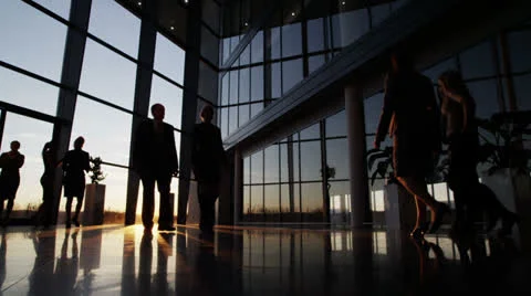 Business people walking through a modern office building at sunset Stock Footage