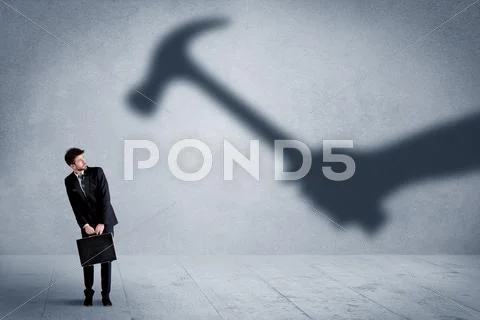 Business person afraid of a shadow hand holding hammer concept Stock Photos