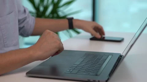 Business person typing on his computer and picking up his smartphone to continue Stock Footage 143560440