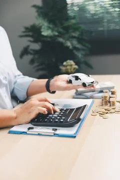 Business person using calculator while reviewing vehicle finance paperwork .. Stock Photos