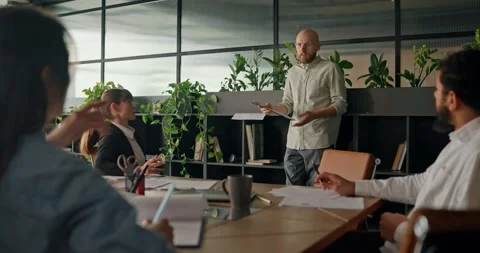 A business professional analyzes data on a tablet presents ideas to colleagues Video stock 307492864