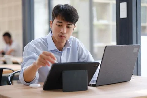 Business professional analyzing data on a tablet and laptop Foto stock