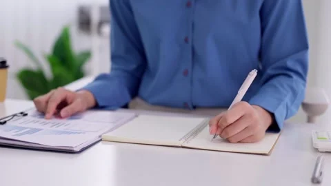 Business professional hand writing notes notebook reviewing financial repor.. Stock Footage 335643408