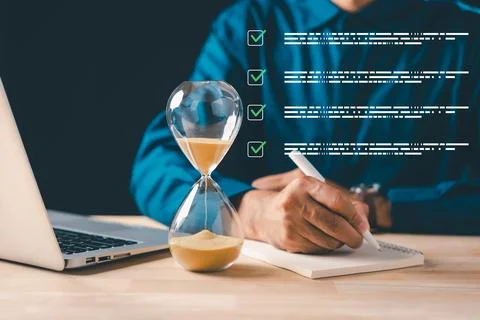Business professional using pen to write notes in book, hourglass showing p.. Stock Photos