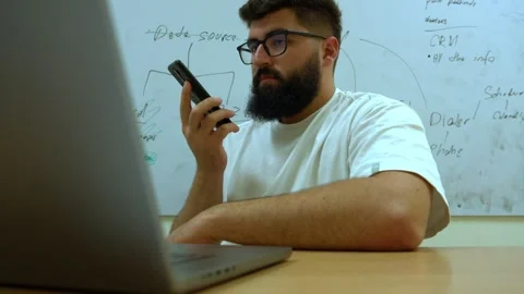 Business professional using smartphone while working on laptop in office Stock Footage 341767954