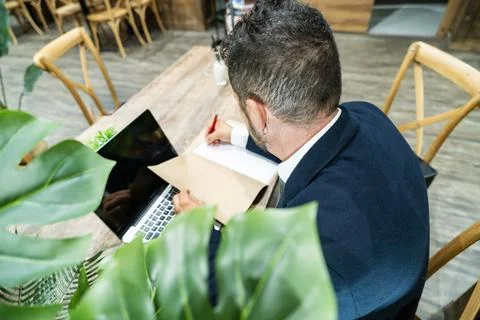 Business professional writing notes while working on laptop in modern offic.. Stock Photos