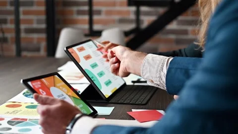 Business professionals analyze data on tablets during a meeting discussing .. Stock Footage 339751732