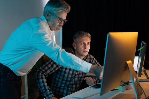Business Professionals Collaborating on Computer in Dimly Lit Office Stock Photos