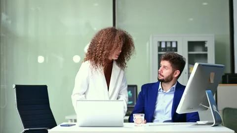 Business professionals discussing work at a desk with laptop and desktop in.. Stockbeeldmateriaal 312386883