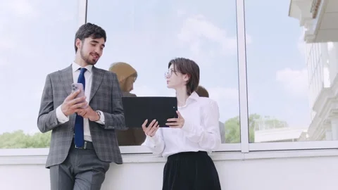 Business professionals engage in conversation while using digital devices Stock Footage 312902420