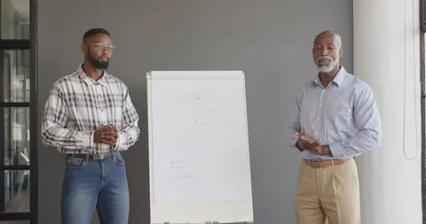 Business professionals presenting financial data on flip chart in modern office Stock Footage 345804773