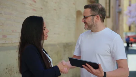 Business professionals shaking hands and smiling at camera after reviewing a Stock Footage 337402416