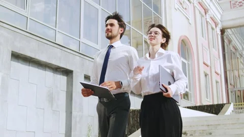 Business professionals walk down steps of modern building discussing project Stock Footage 316048059